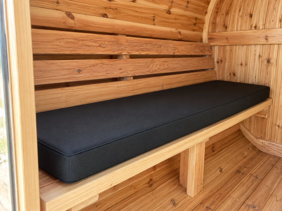 Close three-quarter view of a fitted black cushion inside a cedar barrel sauna