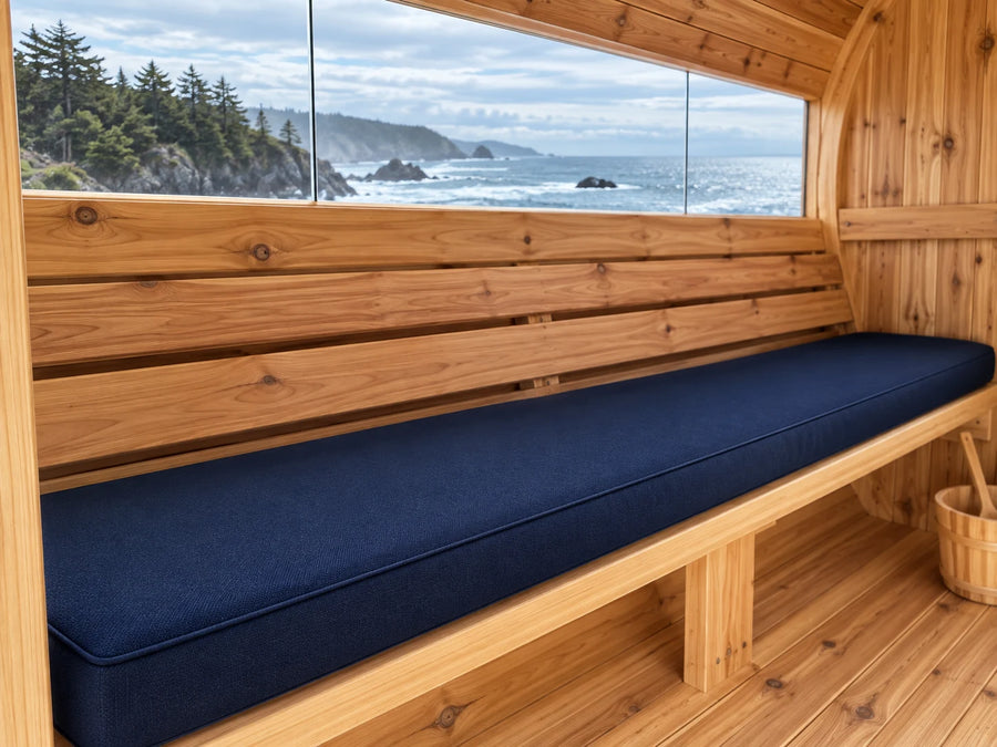 Navy cushion on a cedar barrel sauna bench with a coastal window view